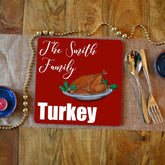 A personalised Christmas placemat with a turkey illustration. the placemat has a red background with white text reading "the Smith family turkey"